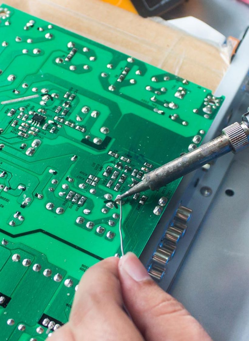 A person working on a circuit board with soldering tools.
